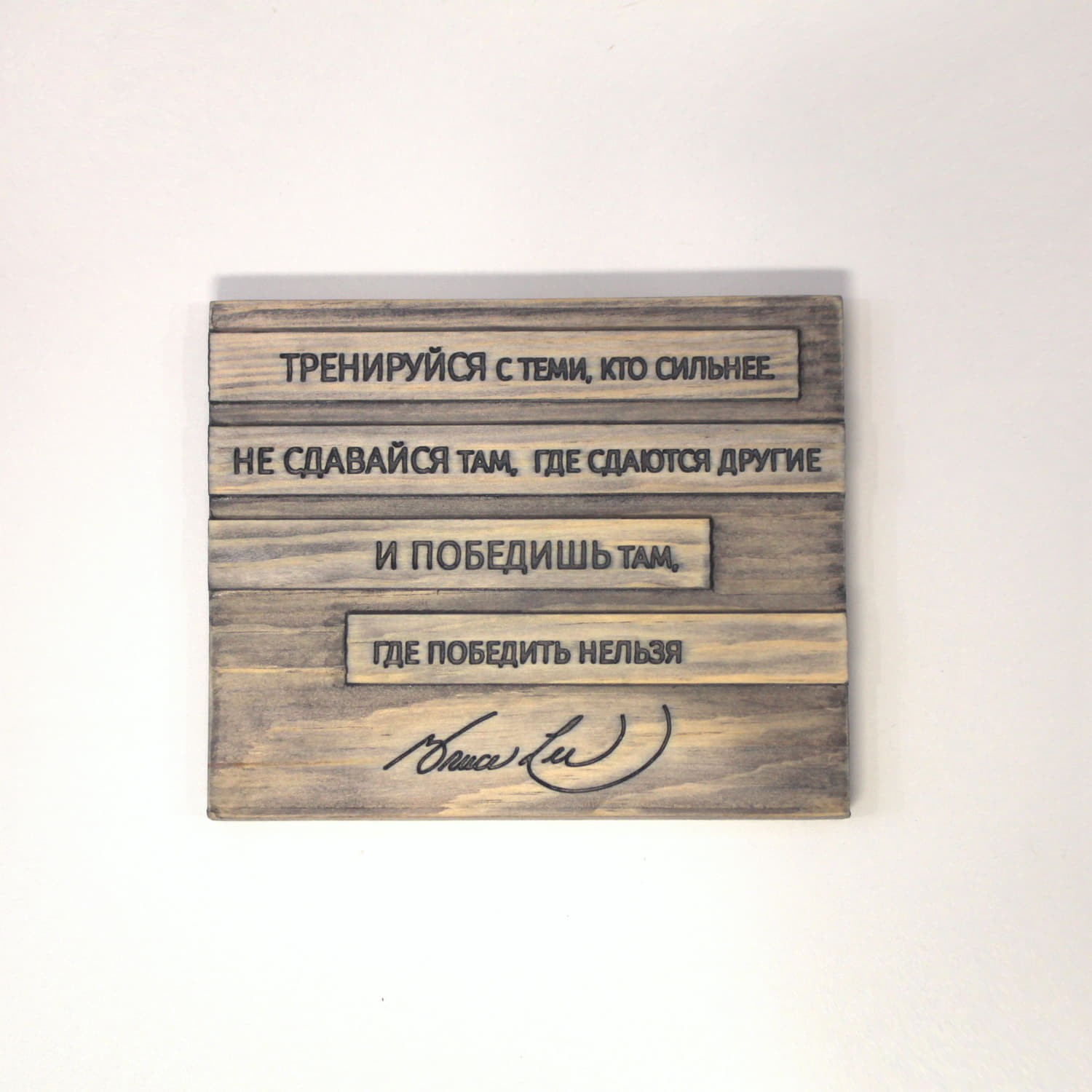 Табличка с цитатой Брюса Ли «Тренируйся с теми, кто сильнее, не сдавайся там, где сдаются другие, и победишь там, где победить нельзя»