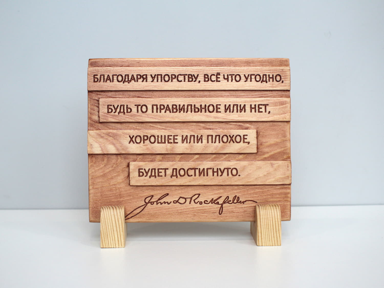 Табличка с цитатой Джона Рокфеллера «Благодаря упорству, все что угодно, будь то правильное или нет, хорошее или плохое, будет достигнуто»