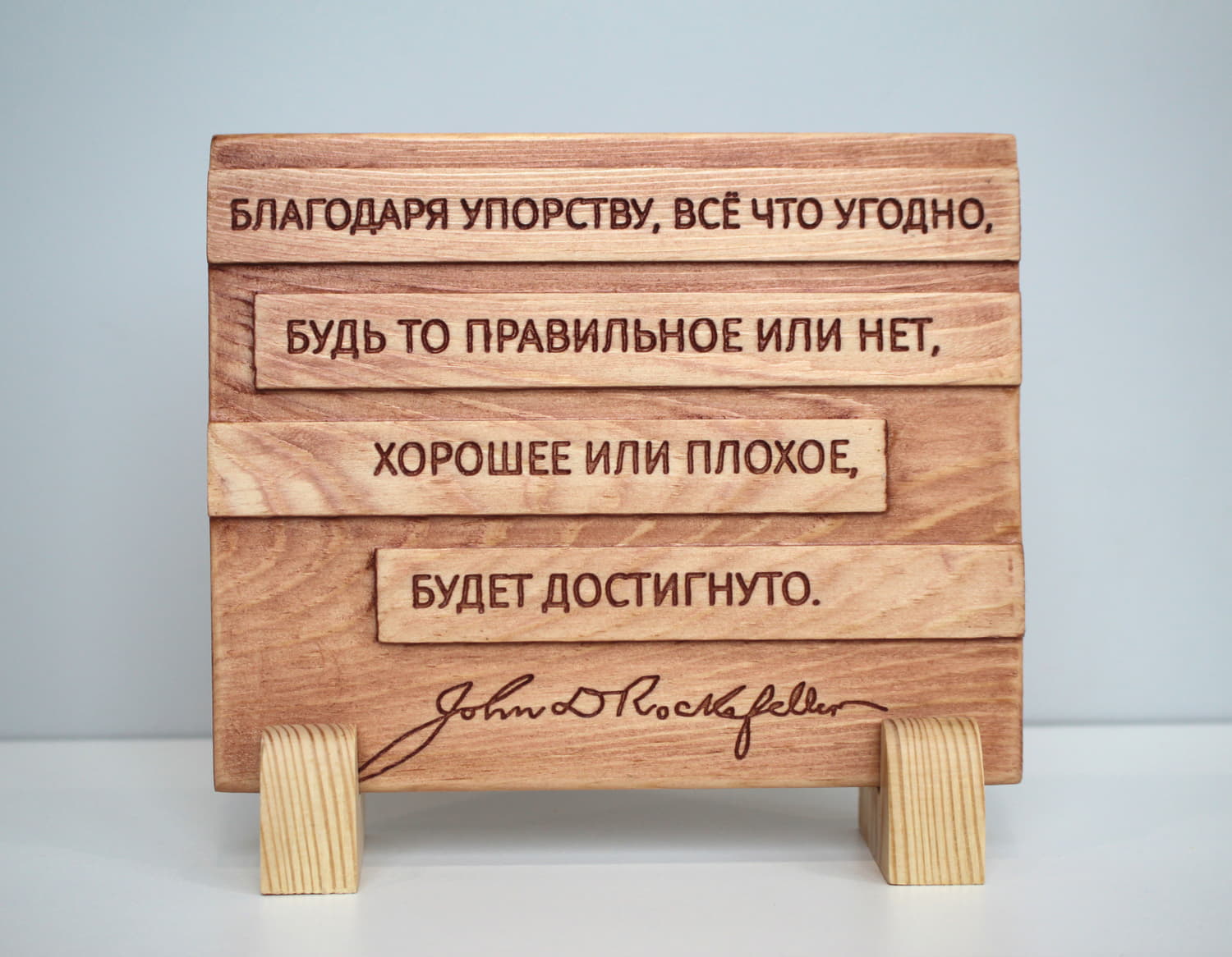 Табличка с цитатой Джона Рокфеллера «Благодаря упорству, все что угодно, будь то правильное или нет, хорошее или плохое, будет достигнуто»