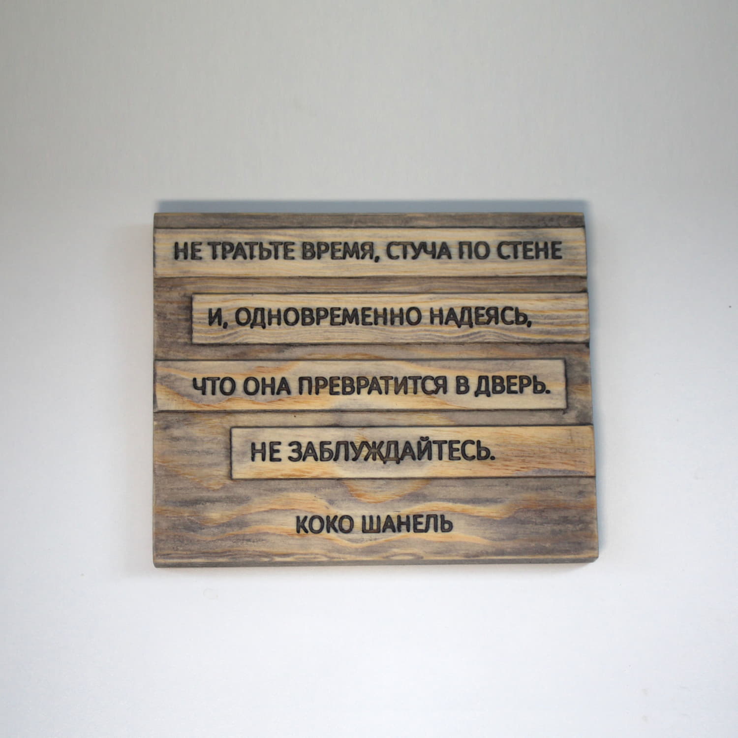 Табличка с цитатой Коко Шанель «Не тратьте время, стуча по стене и, одновременно надеясь, что она превратится в дверь. Не заблуждайтесь»